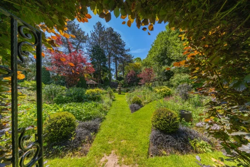 Garden arch framing a path through the mature grounds at Fieldhead, Prestbury